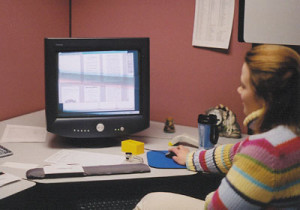 Fig. 6. Data Conversion Manager Korrie Heiden checks several pages in a document and links them together electronically. Boxes of forty-year-old microfiche—the source material for this project—sit on the desk to the lower left of the picture.