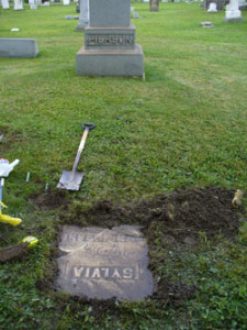 Fig. 8. Sylvia’s gravestone in Vienna Center Cemetery, Vienna, Ohio. Courtesy of the author. In addition to finding water, metal dowsing rods apparently will indicate the presence of a grave, by crossing into an X when you walk over one, holding the rods parallel before you. Even spookier, if you hold one rod perpendicular to the ground over a grave, it will move either clockwise or counter-clockwise depending on the sex of the body underneath. Unbelievably, this worked for me in a blind test. Having previously narrowed down the likely area, Sally dowsed for a grave where Sylvia ought to be, and in no time, her rods were magically crossing into an X. Gently using the trowel to pry aside the lawn, we found a flattened gravestone. Scrubbing off some mud and was