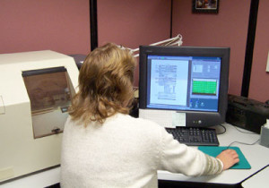 Fig. 2. Kelly Lauren monitors input from the Mekel scanner after feeding fiche through the clear plastic portal on the left. The green square on the right represents the entire microfiche, and the larger image shown on the left is one page scanned from it.