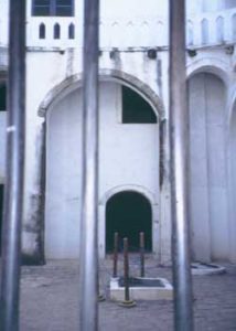 Fig. 10. The courtyard surrounded by female dungeons at Elmina Castle. A cistern used to hold drinking water is in the center. The upper balcony is connected to the governor's quarters, overlooking where the women were kept. The photograph is taken through (new) iron bars on arched windows of the female dungeons.